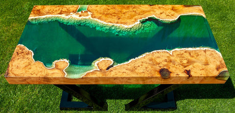 Wooden table with green resin inlay on a grassy background